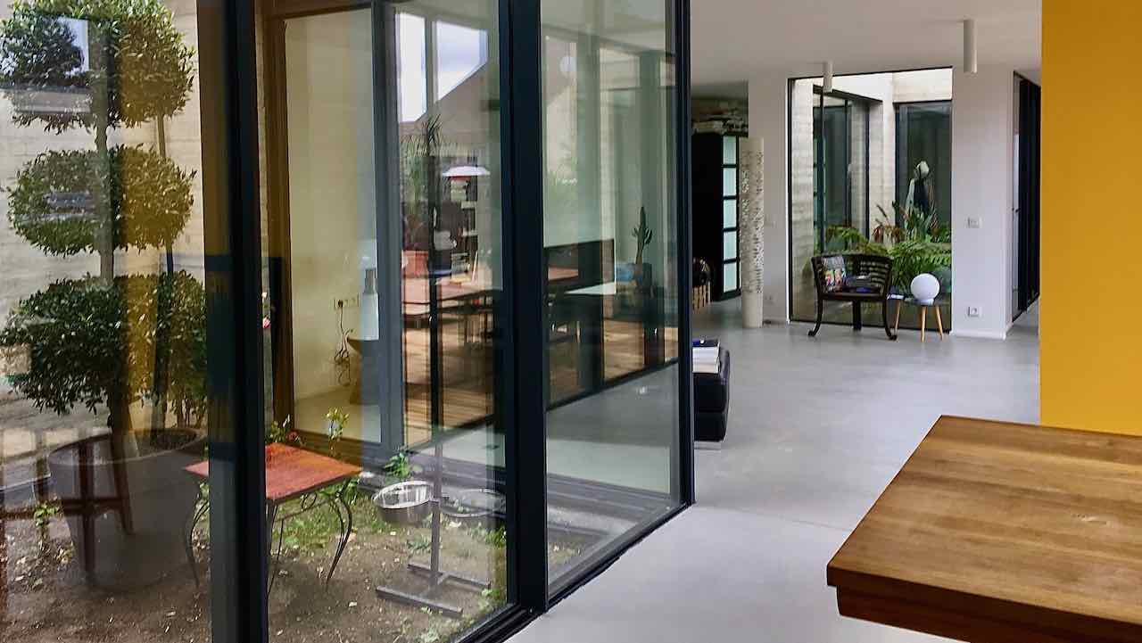 Maison contemporaine avec patio intérieru totalement vitré avec fenêtres coulissantes minimalistes en angle